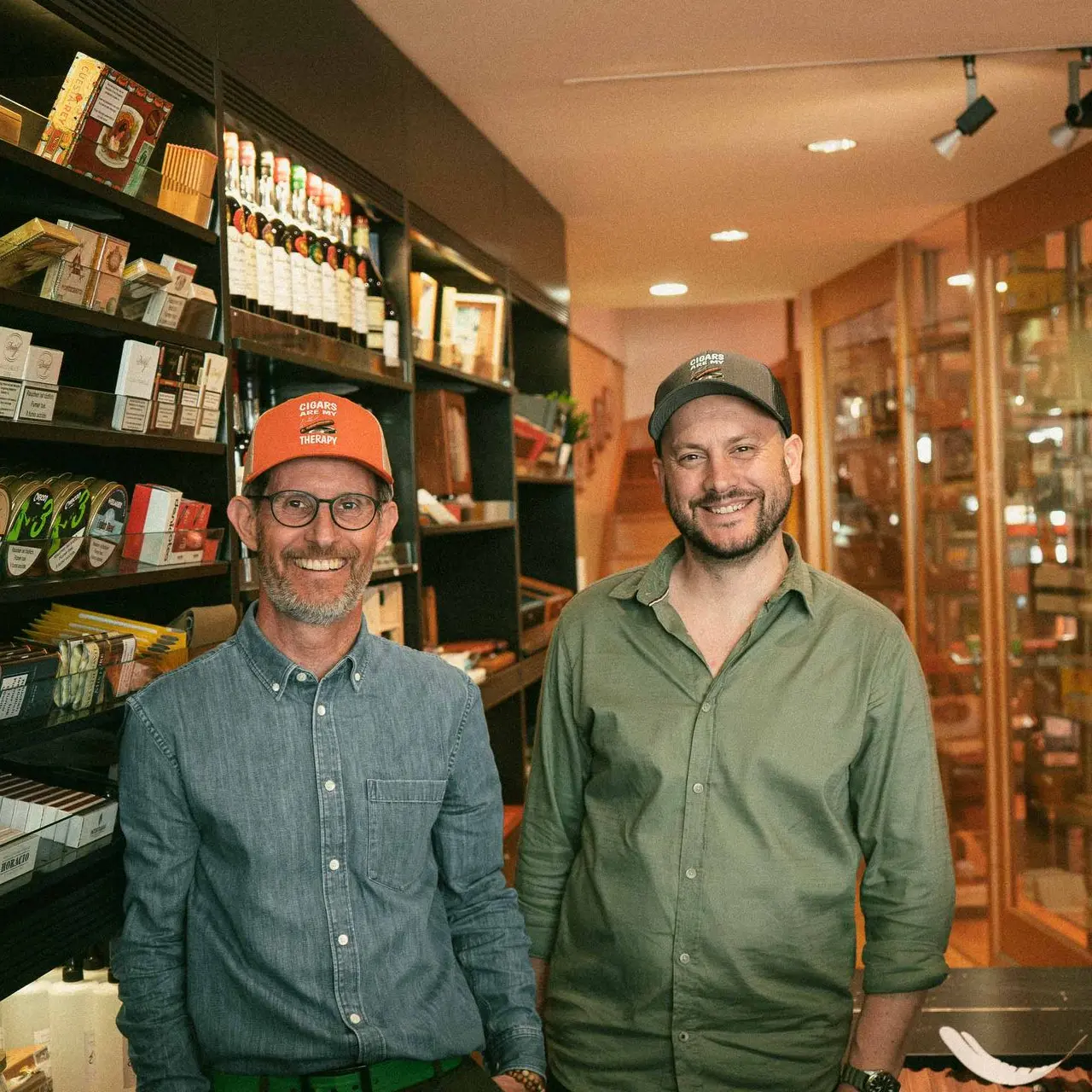 Histoires de Cigares owner and staff in front of spirits selection and cigar humidor